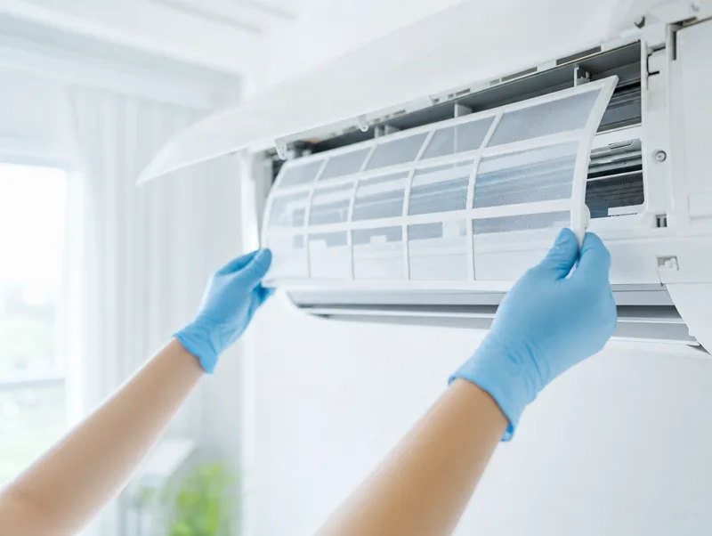 Technician sliding a clean filter out of a wall-mounted aircon unit